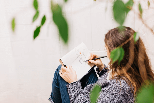 A woman drawing in her art journal